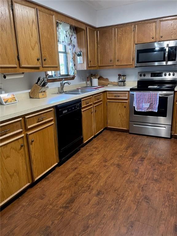 kitchen with stainless steel appliances, dark wood-type flooring, and sink