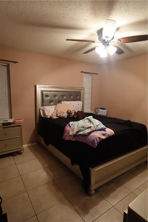 bedroom with light tile patterned floors, a textured ceiling, and ceiling fan