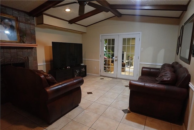 tiled living room featuring french doors, vaulted ceiling with beams, ceiling fan, a textured ceiling, and a tiled fireplace