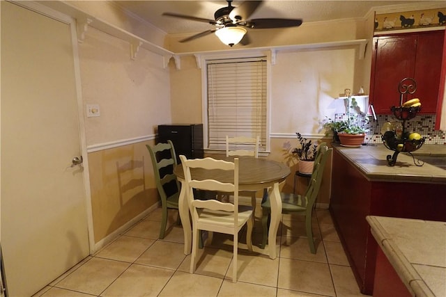 tiled dining area featuring ceiling fan and crown molding