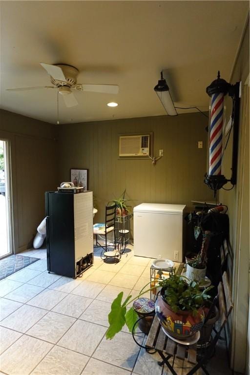 interior space with an AC wall unit, ceiling fan, and light tile patterned flooring