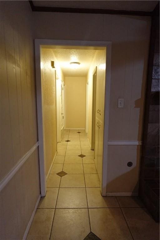 hallway with light tile patterned floors, a textured ceiling, and wooden walls