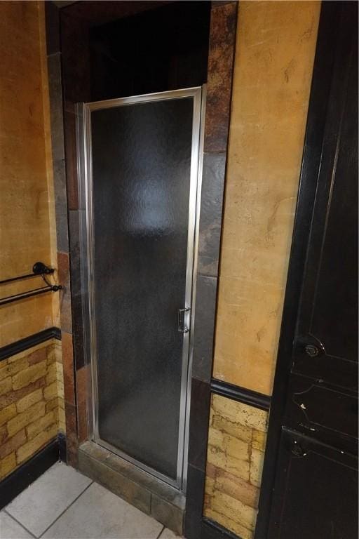 bathroom featuring tile patterned flooring, an enclosed shower, and brick wall