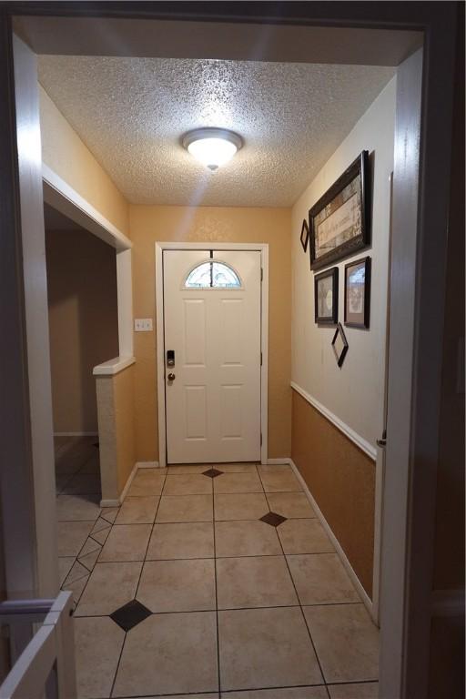 doorway to outside with light tile patterned floors and a textured ceiling