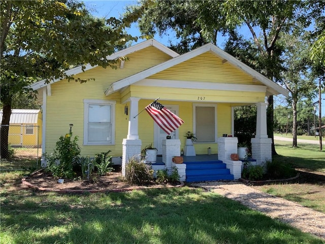 bungalow featuring covered porch and a front yard