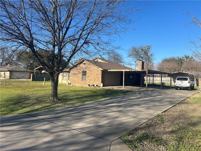 view of side of home with brick siding, a lawn, concrete driveway, and a chimney