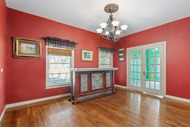 interior space featuring hardwood / wood-style floors, a textured ceiling, french doors, and a notable chandelier