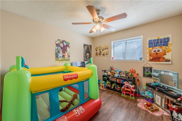 playroom with a textured ceiling, dark hardwood / wood-style floors, and ceiling fan