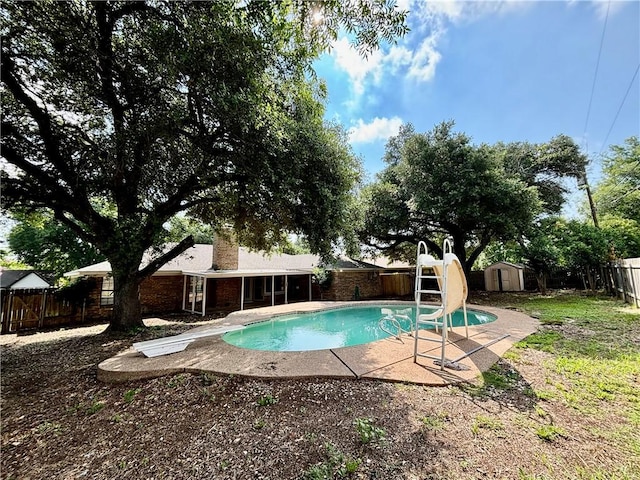 view of swimming pool with a diving board, a storage shed, and a water slide