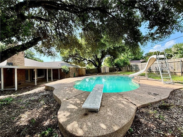 view of swimming pool with a patio area, a diving board, and a water slide