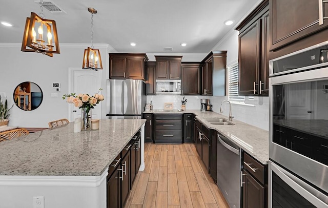 kitchen with a kitchen island, a sink, visible vents, appliances with stainless steel finishes, and light wood-type flooring