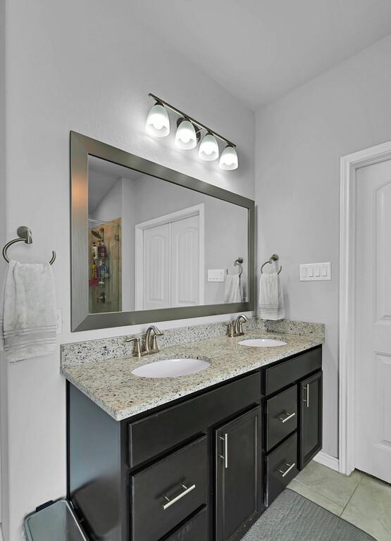 bathroom with tile patterned flooring, a sink, and double vanity