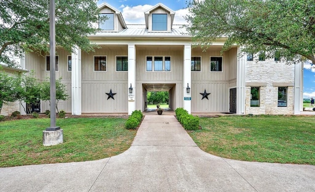 view of front of house featuring metal roof, stone siding, a front lawn, and a standing seam roof