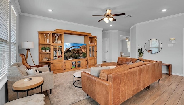 living area with a ceiling fan, visible vents, baseboards, ornamental molding, and light wood finished floors