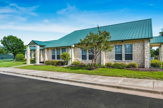 view of front of property with metal roof, stone siding, and a front lawn