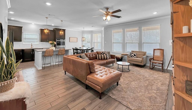 living area with crown molding, recessed lighting, visible vents, and light wood-style floors