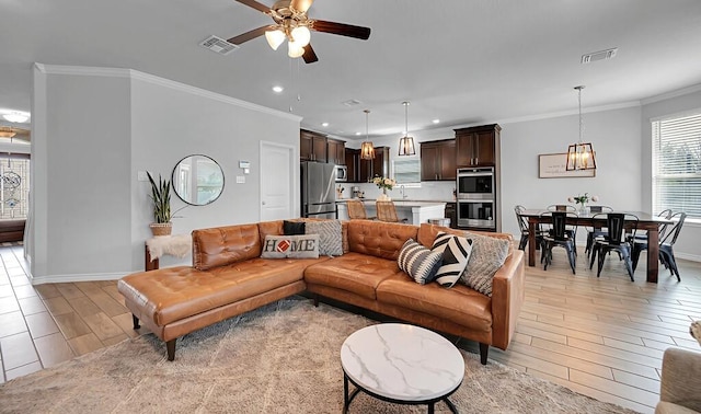 living room featuring light wood-type flooring, visible vents, and crown molding