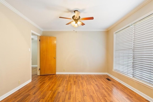 empty room featuring a healthy amount of sunlight, ornamental molding, and light hardwood / wood-style flooring