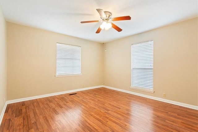 spare room with ceiling fan, plenty of natural light, and hardwood / wood-style floors