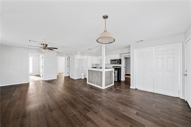 unfurnished living room featuring dark wood-type flooring and ceiling fan