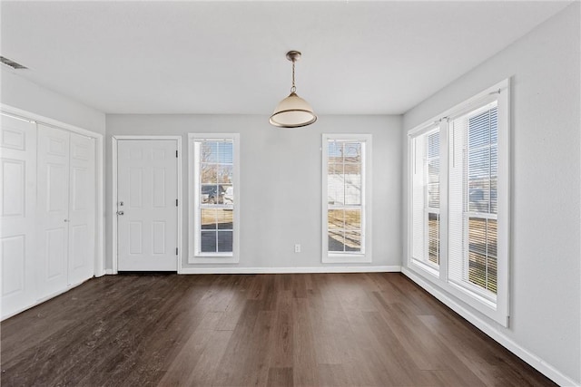 unfurnished dining area with dark wood-type flooring