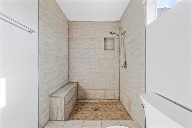 bathroom featuring a tile shower and toilet