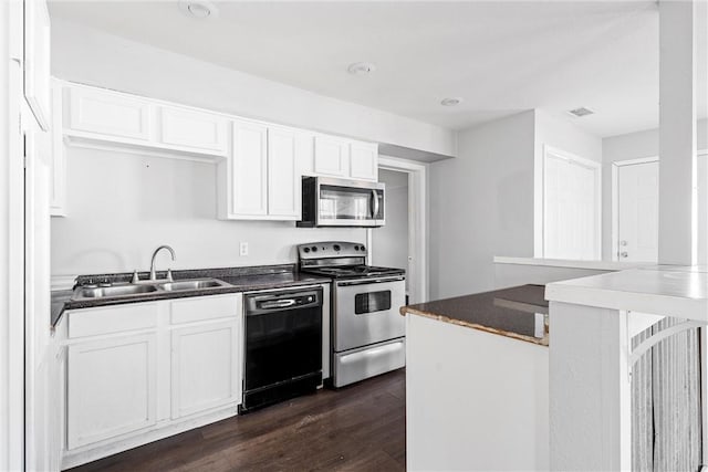 kitchen featuring appliances with stainless steel finishes, sink, white cabinets, and dark hardwood / wood-style flooring