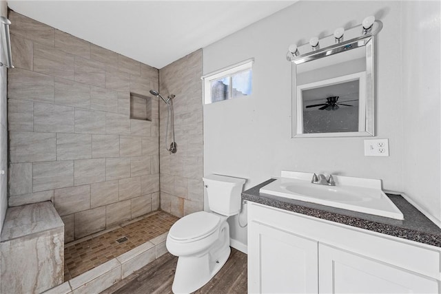 bathroom featuring tiled shower, vanity, toilet, and wood-type flooring