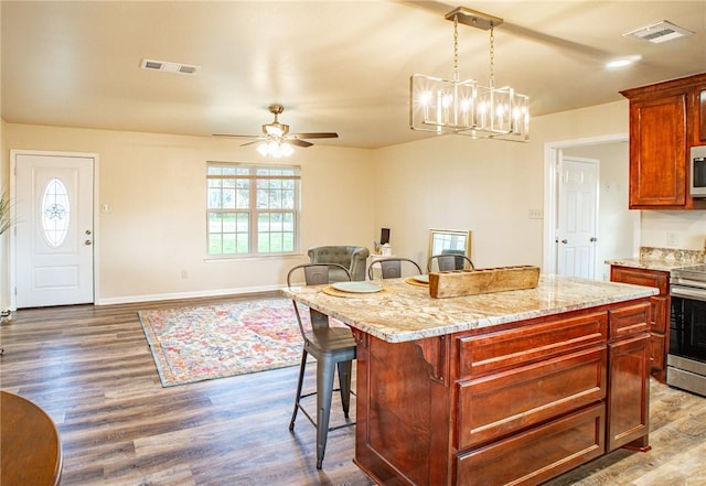 kitchen with hanging light fixtures, a kitchen island, a breakfast bar area, and appliances with stainless steel finishes