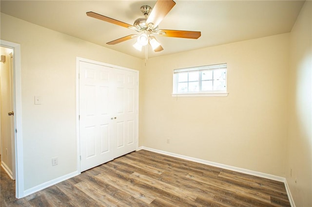 unfurnished bedroom with dark hardwood / wood-style flooring, a closet, and ceiling fan