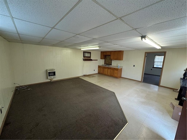 interior space with heating unit, light floors, baseboards, and a drop ceiling