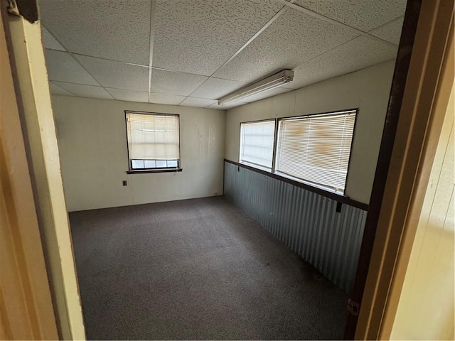 carpeted empty room with plenty of natural light and a paneled ceiling