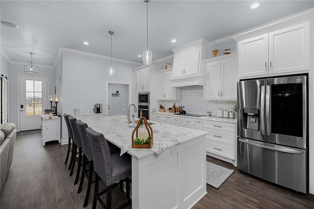 kitchen featuring white cabinets, decorative light fixtures, stainless steel appliances, and a kitchen island with sink