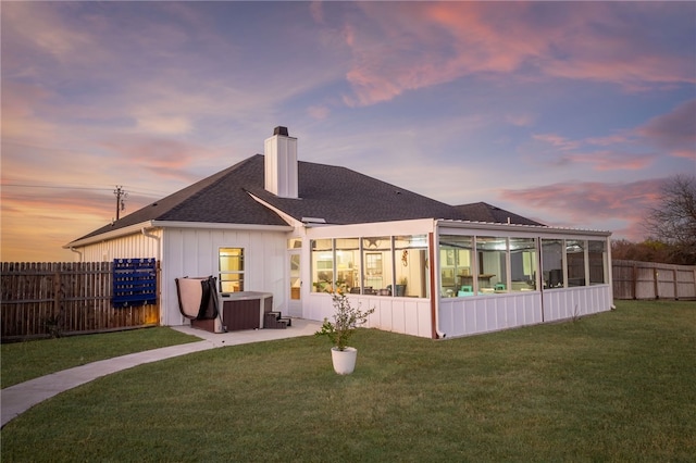 back house at dusk featuring a yard and a sunroom