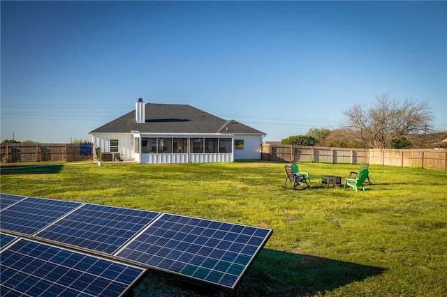 back of property with solar panels, a yard, and a sunroom