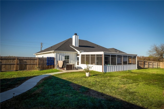 rear view of house with a lawn, a sunroom, and central AC unit