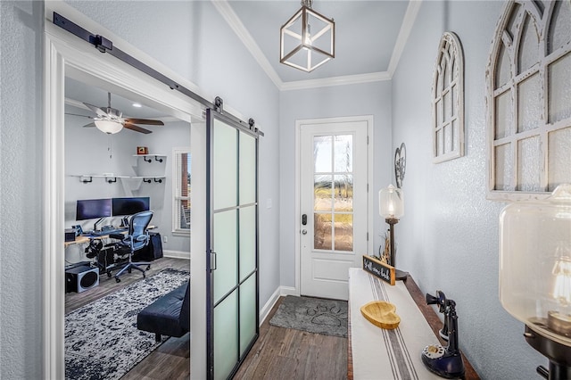 entryway with a barn door, dark hardwood / wood-style floors, ceiling fan, and ornamental molding