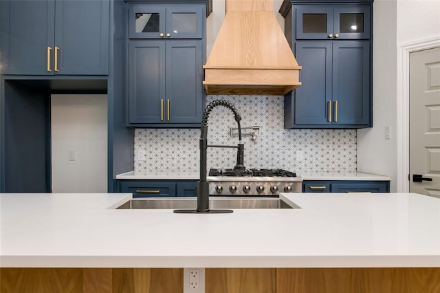 kitchen with tasteful backsplash, sink, custom range hood, and blue cabinets