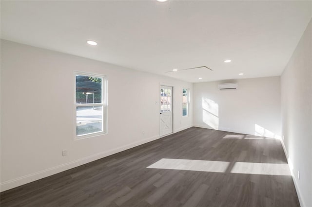 unfurnished room with dark hardwood / wood-style floors, an AC wall unit, and plenty of natural light