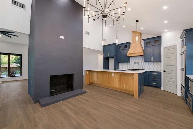 kitchen featuring a fireplace, custom range hood, a towering ceiling, and dark wood-type flooring