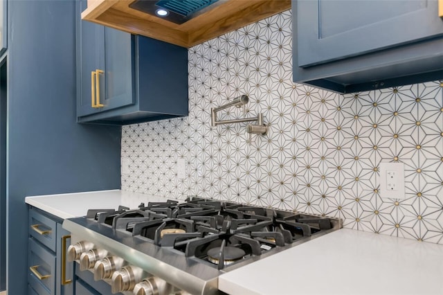 interior details featuring stainless steel range, backsplash, blue cabinets, and range hood