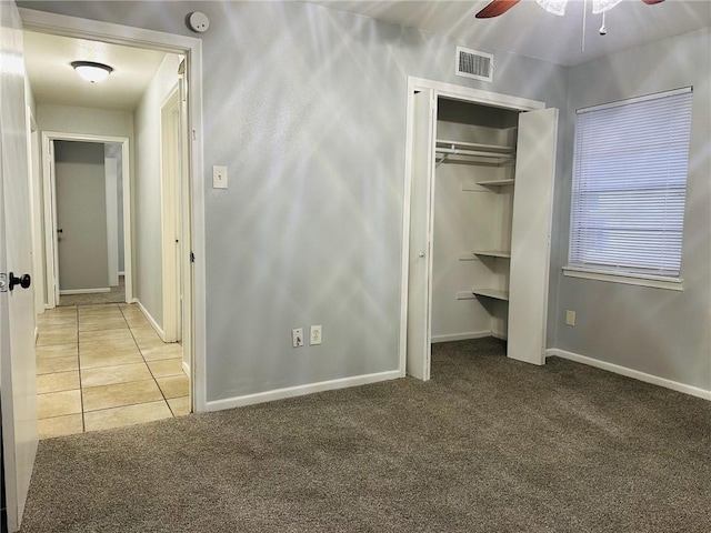 unfurnished bedroom featuring ceiling fan, light colored carpet, and a closet