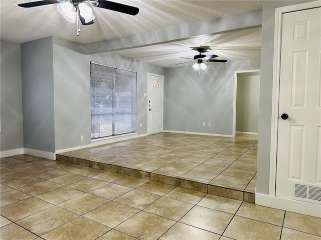 empty room with light tile patterned floors, a textured ceiling, and ceiling fan