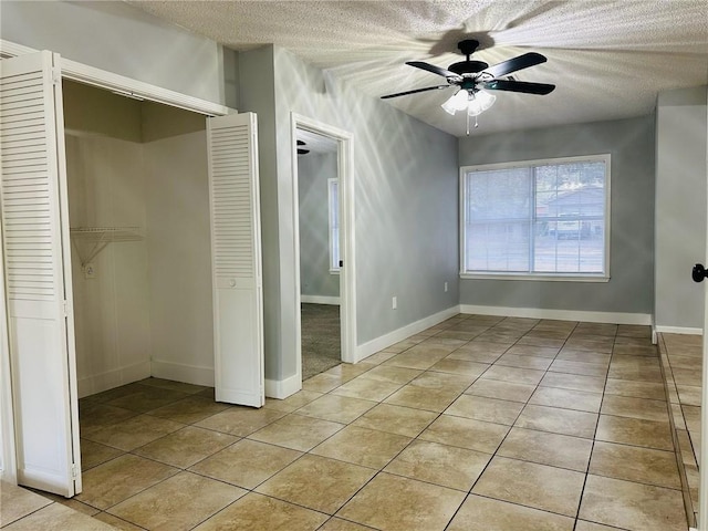 unfurnished bedroom with a textured ceiling, a closet, ceiling fan, and light tile patterned flooring