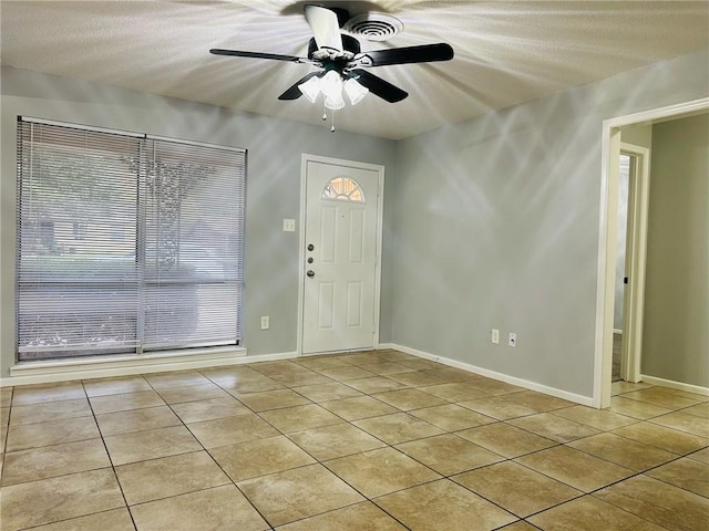 foyer featuring ceiling fan, light tile patterned flooring, and a textured ceiling