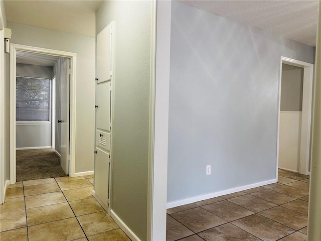 corridor featuring light tile patterned floors and a textured ceiling