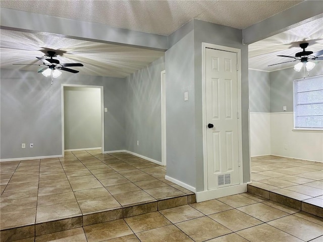 spare room featuring a textured ceiling, ceiling fan, and light tile patterned flooring