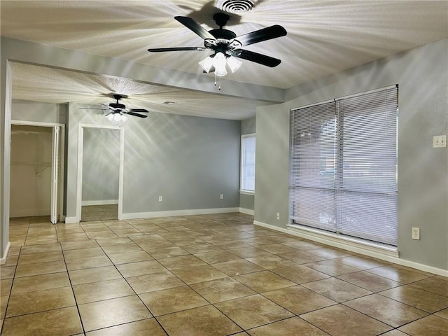 tiled empty room featuring ceiling fan and a textured ceiling