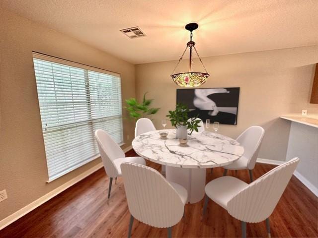 dining space featuring a textured ceiling and dark hardwood / wood-style floors