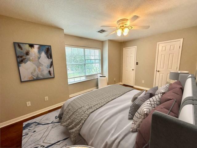 bedroom with ceiling fan, hardwood / wood-style floors, and a textured ceiling